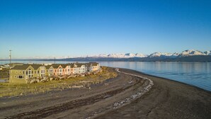 Fileira de casas à beira de um lago, com montanhas ao fundo.