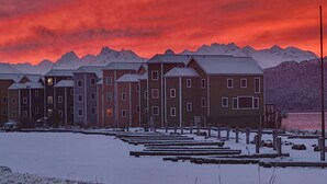 En rad höga byggnader med ett snötäckt förgrund och berg i bakgrunden.
