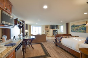 A hotel room with a bed, a dining table, a kitchen area, and a TV.