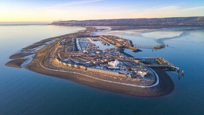 Vue aérienne d’une zone industrielle côtière, avec un quai, des entrepôts et une darse.