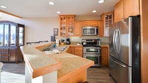 A kitchen with wooden cabinets, a stainless steel refrigerator, a microwave, an oven, and a granite countertop.