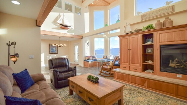 Un salón amplio con techo alto, chimenea y vistas al mar.