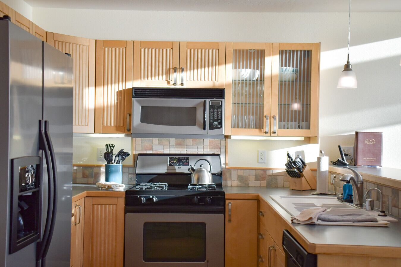 A modern kitchen with wooden cabinets, stainless steel appliances, and a gas stove.