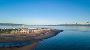 A coastal area with a row of colorful houses along the shore, a sandy beach, and a calm body of water.