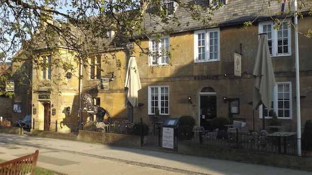 A traditional stone building with a sign for 'Russell's' indicating it is a cafe. There are outdoor tables and chairs, and a metal fence surrounding the seating area. - Two Bedroom Timber Lodge, Avonvale Holiday Lodges (Evesham)