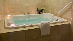 Eine Badewanne mit Kerzen, einer Champagnerflasche und einem Blumenstrauß.