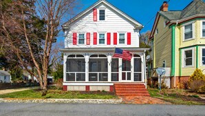 Une maison à deux étages avec un porche et un drapeau.