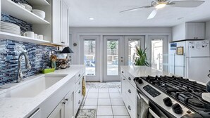 Eine moderne Küche mit weißen Schränken, einem Gasherd und einem Deckenventilator.