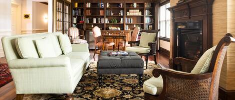 A cozy living room with a large bookshelf, a fireplace, and comfortable seating.