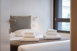 Un lit bien fait, avec du linge de lit blanc et une pile de serviettes pliées.