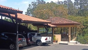 Un estacionamiento con marquesina cubierta, un edificio con techo de tejas y un sendero pavimentado.