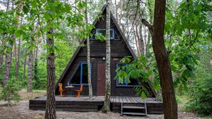 A cabin with a wooden deck, a door, and two windows.