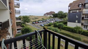 Een woongebied met een parkeerplaats, een heuvel op de achtergrond en een gebouw met meerdere balkons.