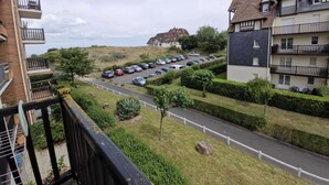 Een woonwijk met een parkeerplaats, een weg en een heuvel, met een gebouw op de achtergrond.