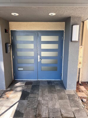 A blue double door with frosted glass panels and a 'No Soliciting' sign.