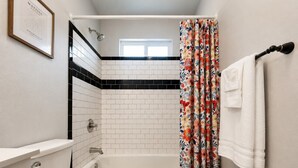 A bathroom with a toilet, sink, bathtub, and shower curtain.