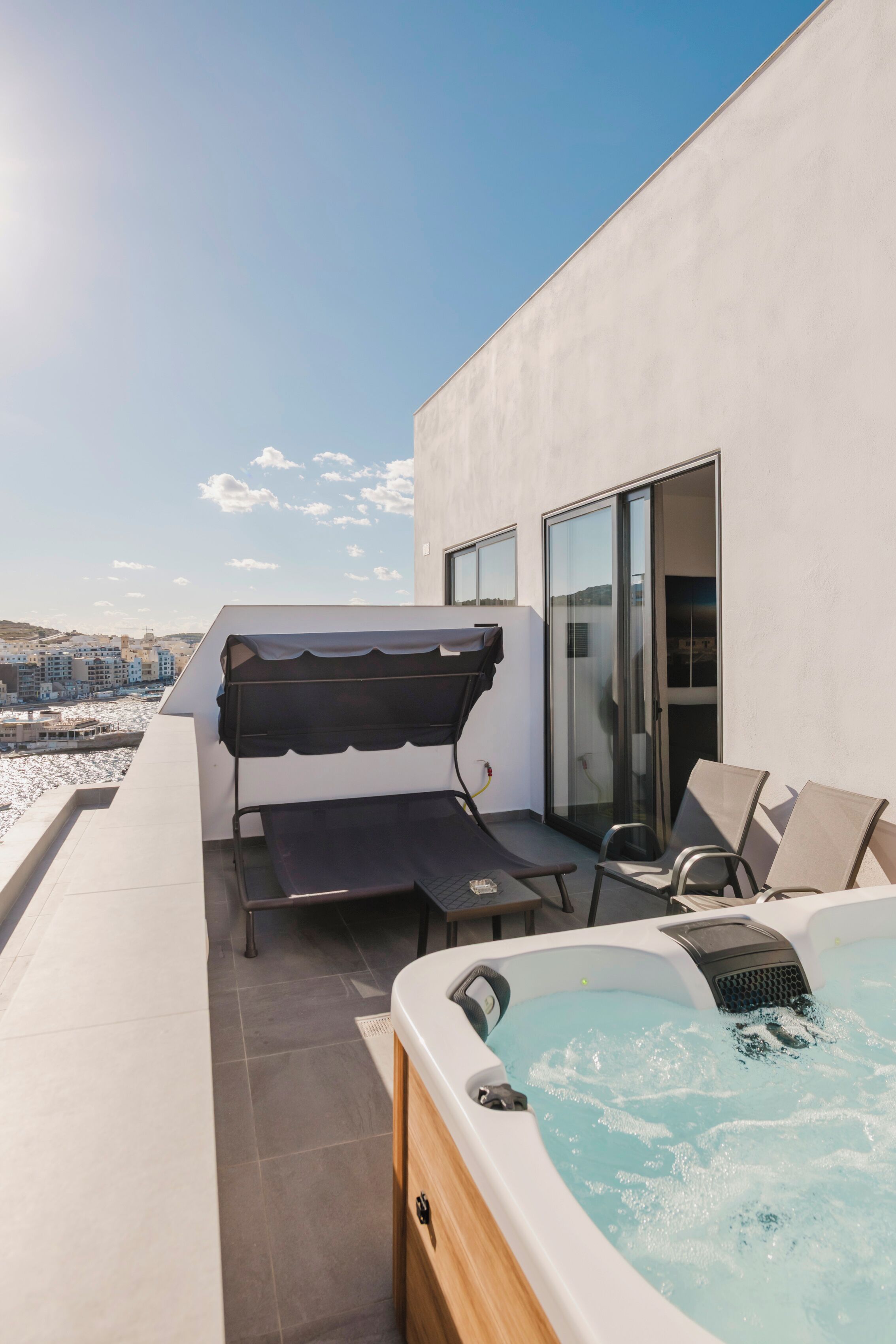 A rooftop terrace with a hot tub, outdoor seating, and a view of the cityscape.