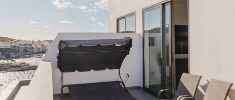 A rooftop terrace with a hot tub, outdoor seating, and a view of the cityscape.