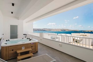 A balcony with a hot tub, a door, and a view of the sea. - Horizon Suites by the Sea (St. Paul's Bay)