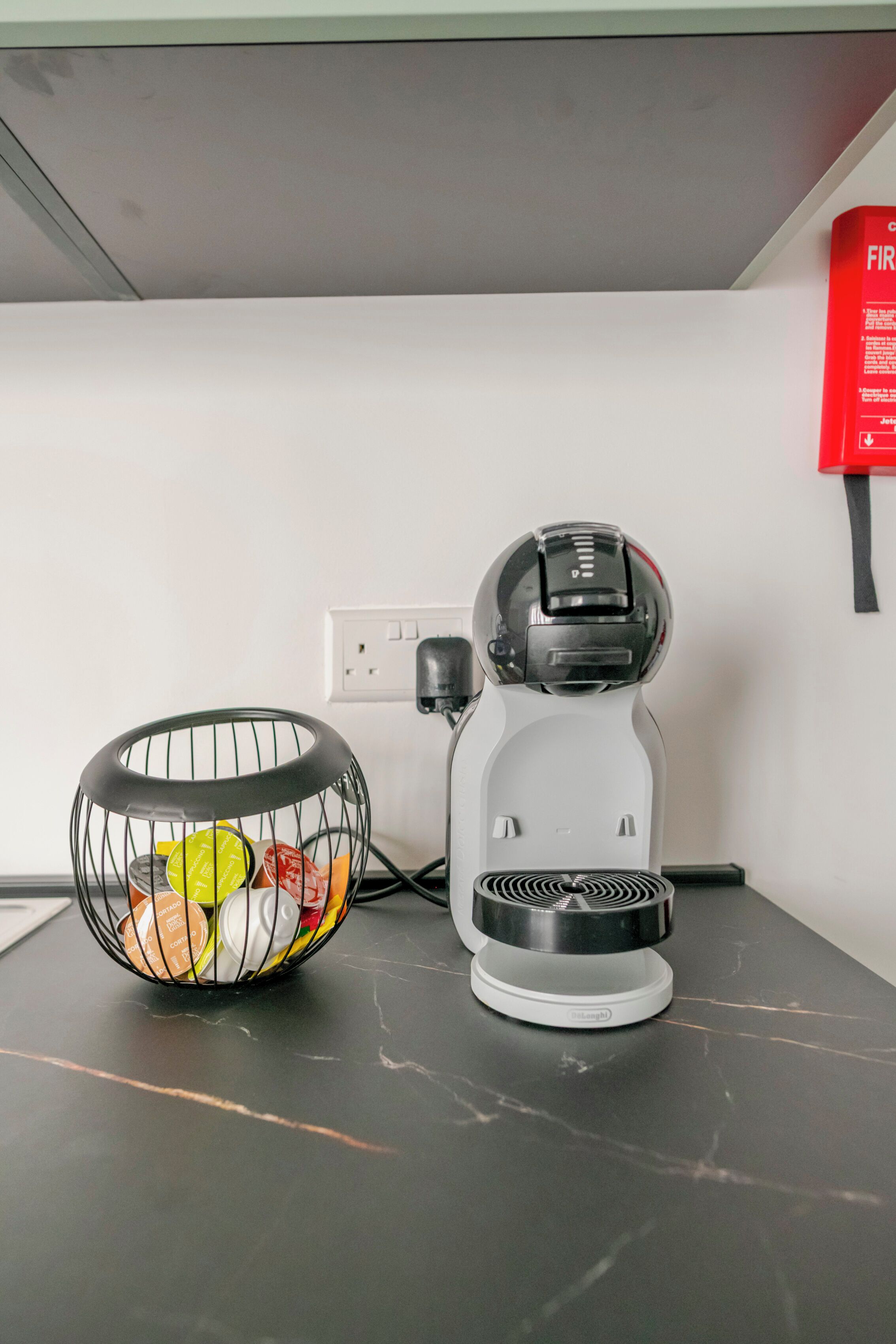 Μια καφετιέρα και ένα καλαθάκι με κάψουλες καφέ πάνω σε ένα τραπέζι.