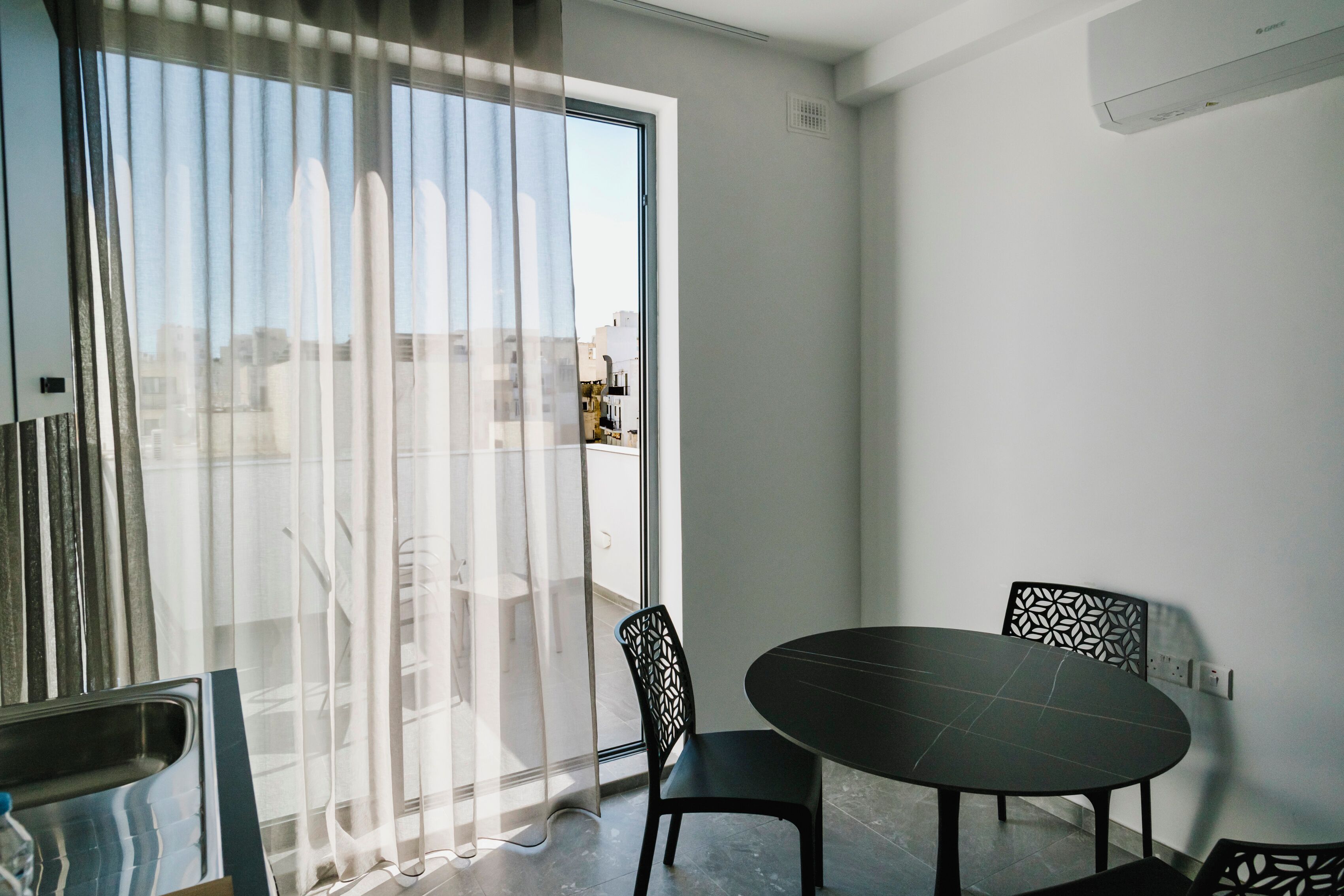 Ein Zimmer mit einer großen Schiebeglastür, einem runden Tisch, zwei Stühlen und einer Steckdose an der Wand.