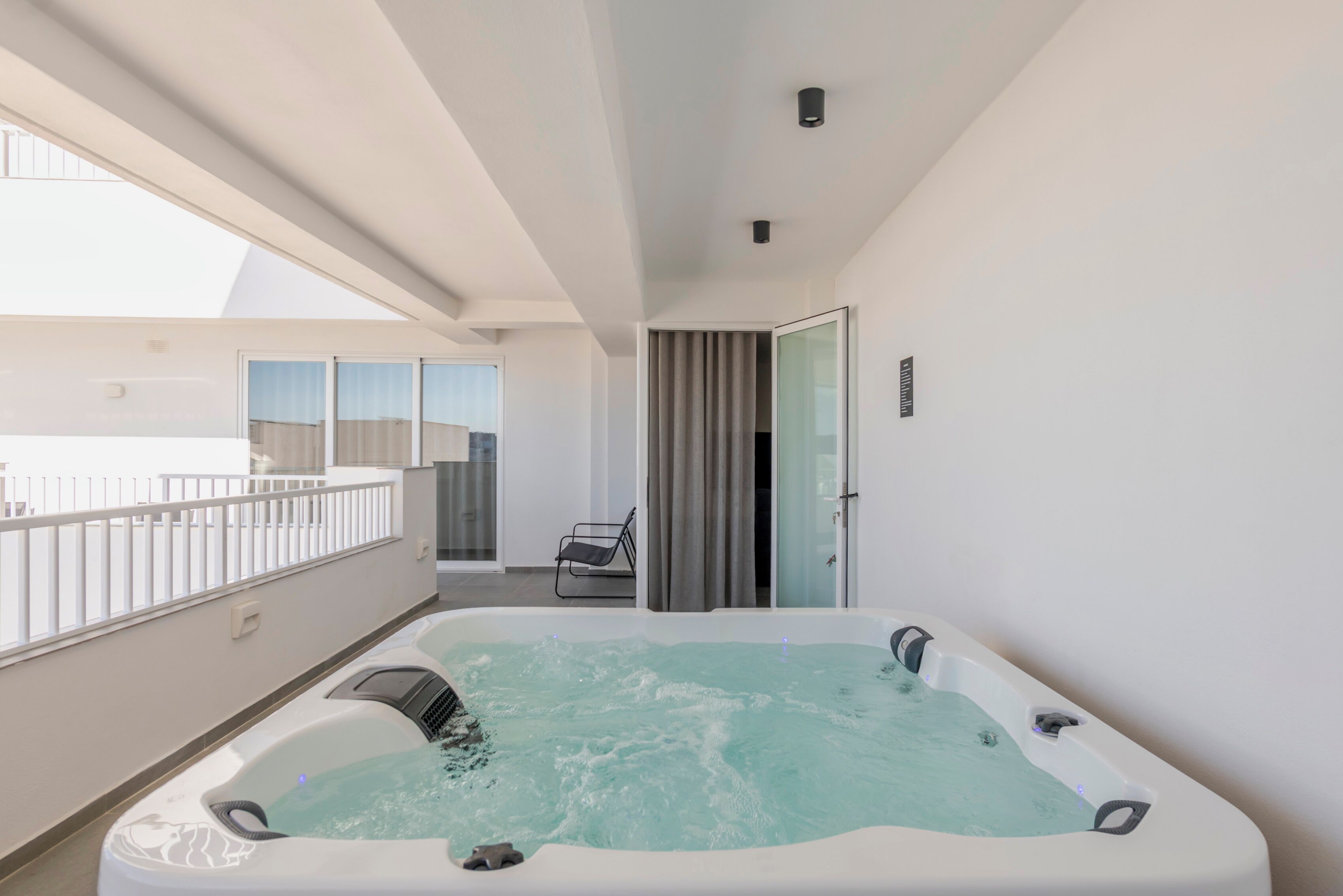 Een moderne badkamer met een ruime badkuip, een douchegedeelte en een balkon met een leuning.