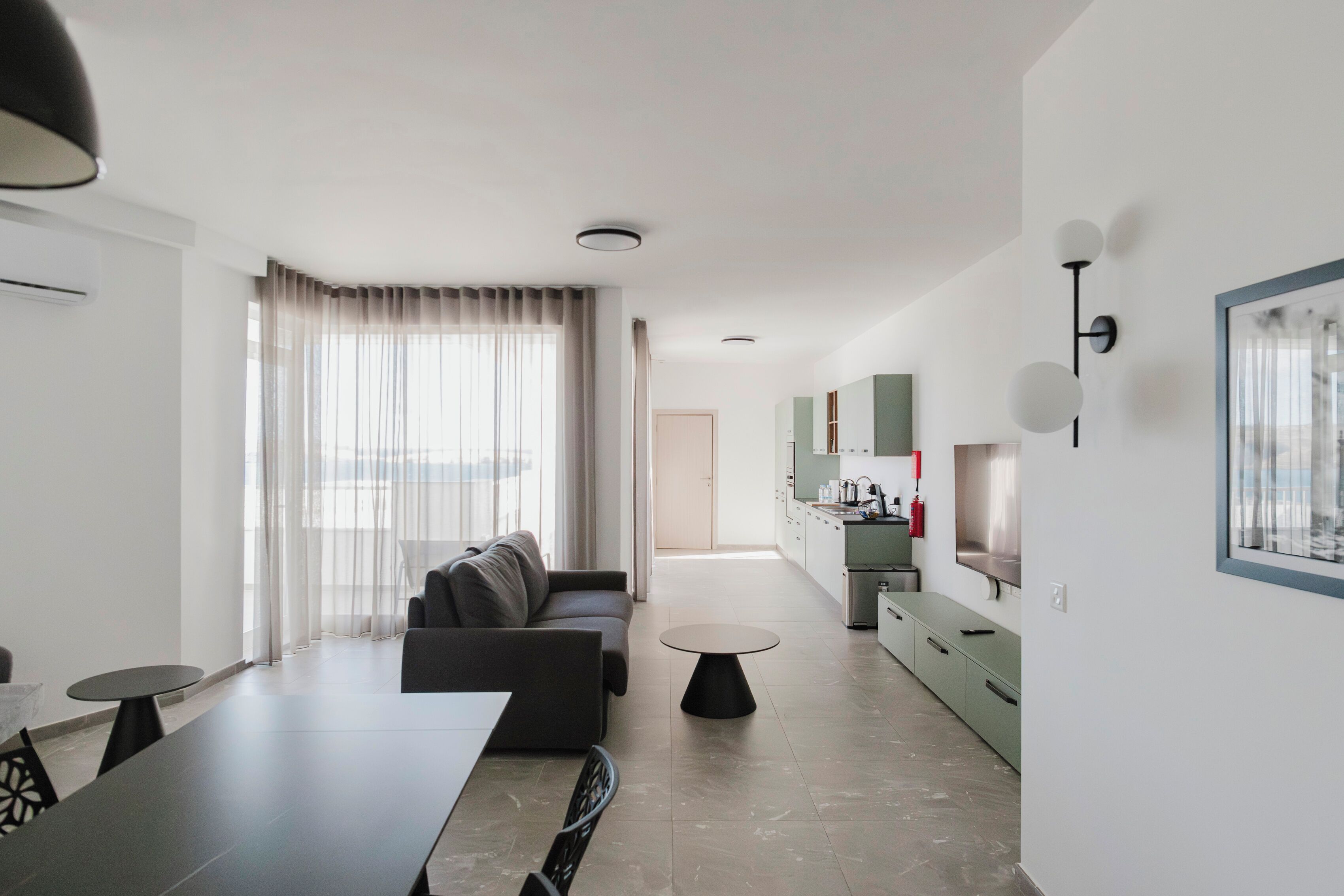 Uma sala de estar moderna com sofá, mesa de jantar e área de cozinha com armários e fogão.