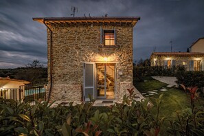 A stone house with a staircase leading to a balcony, surrounded by greenery. - Beautifully restored farmhouse with private pool, Wi-Fi, and air conditioning. (Arezzo)