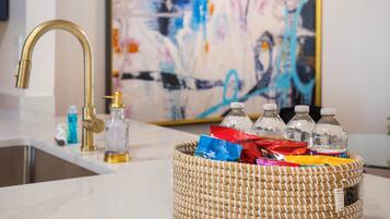 A kitchen with a modern faucet, a woven basket with snacks, and a colorful abstract painting on the wall.