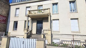 A building with a balcony, a door, and a staircase leading to the entrance. - Charming apartment just steps from the beach (Saint-Malo)