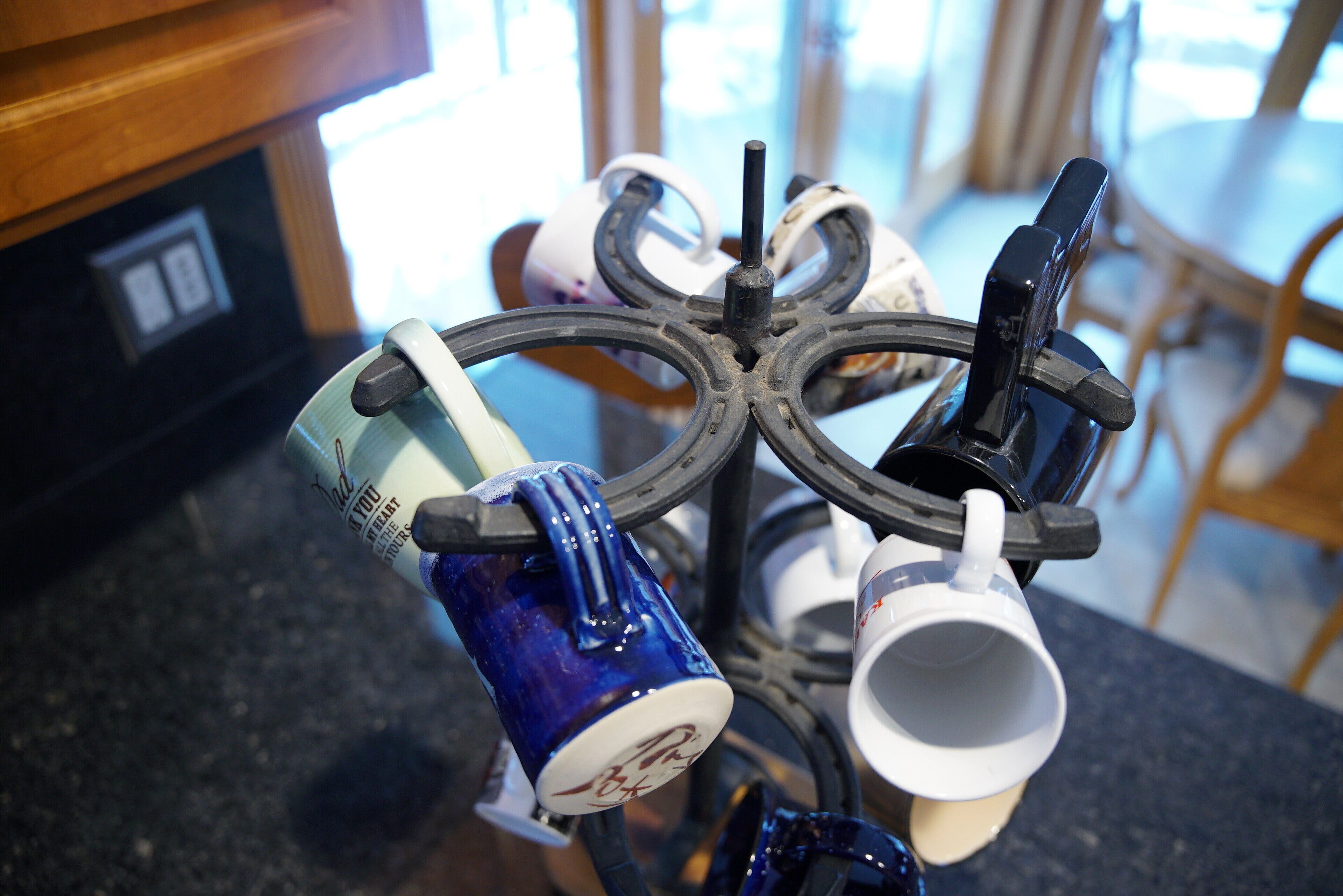 Une machine à café avec plusieurs tasses, un meuble en bois et une fenêtre en arrière-plan.