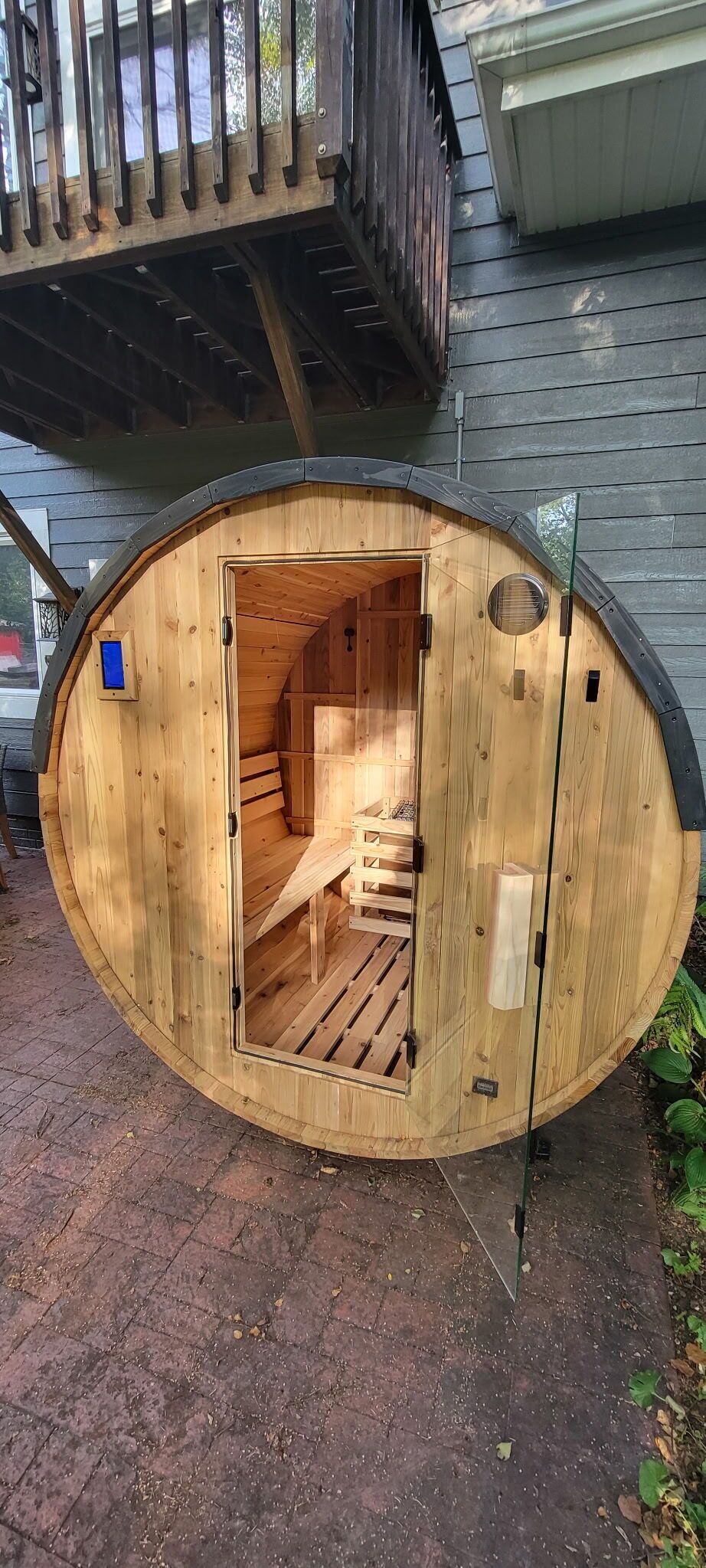 A wooden sauna structure with a bench inside, a small window, and a door.