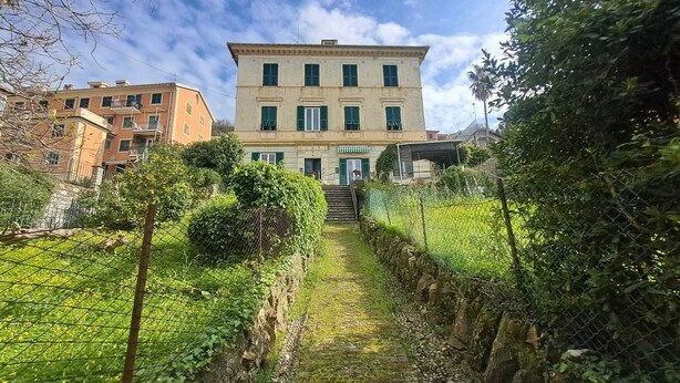 A building with a stone pathway leading to a door, surrounded by greenery and fences. - Central Design Flat With Parking  (Bogliasco)