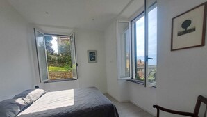 A bedroom with a bed, a chair, and two windows. - Central Design Flat With Parking  (Bogliasco)