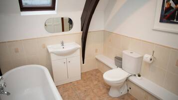 A bathroom with a bathtub, sink, toilet, and a window above the sink.