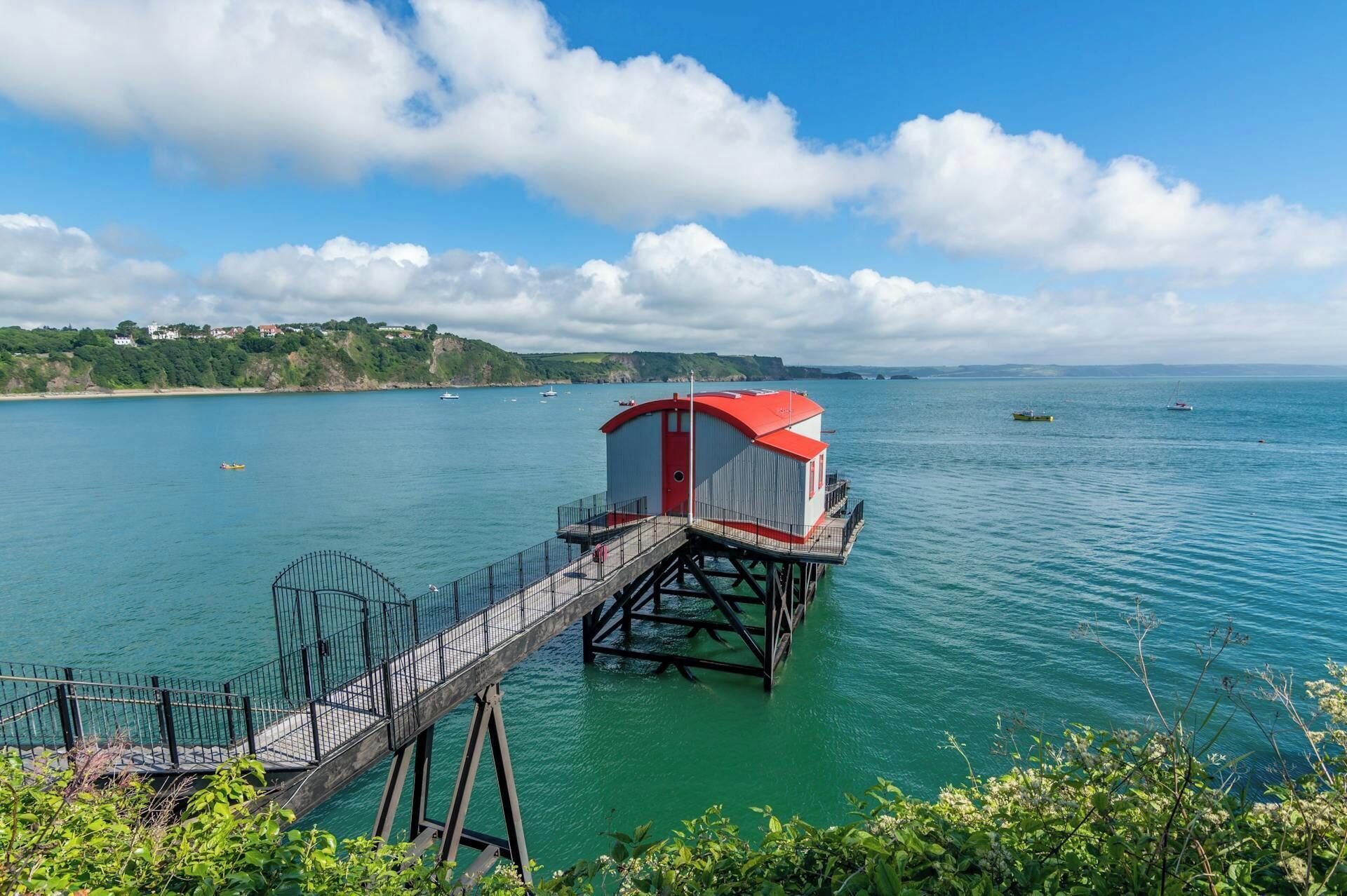 Un muelle que conduce a un edificio de techo rojo con barandilla de metal.