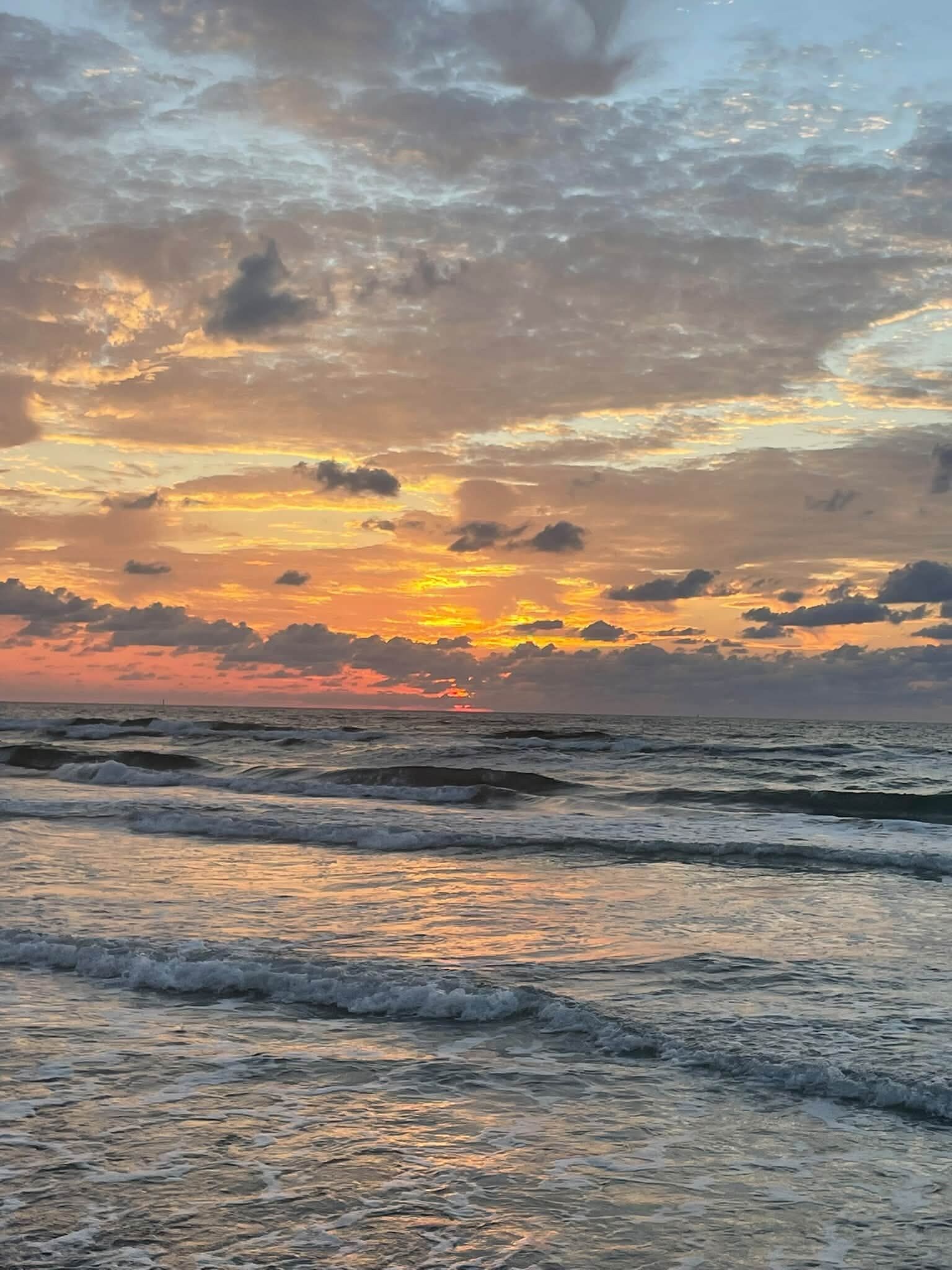 A beach with waves and a sunset.
