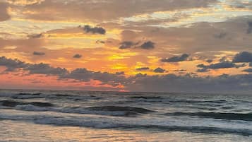 A beach with waves and a sunset.
