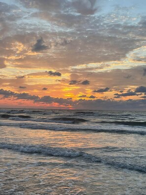 A beach with waves and a sunset.