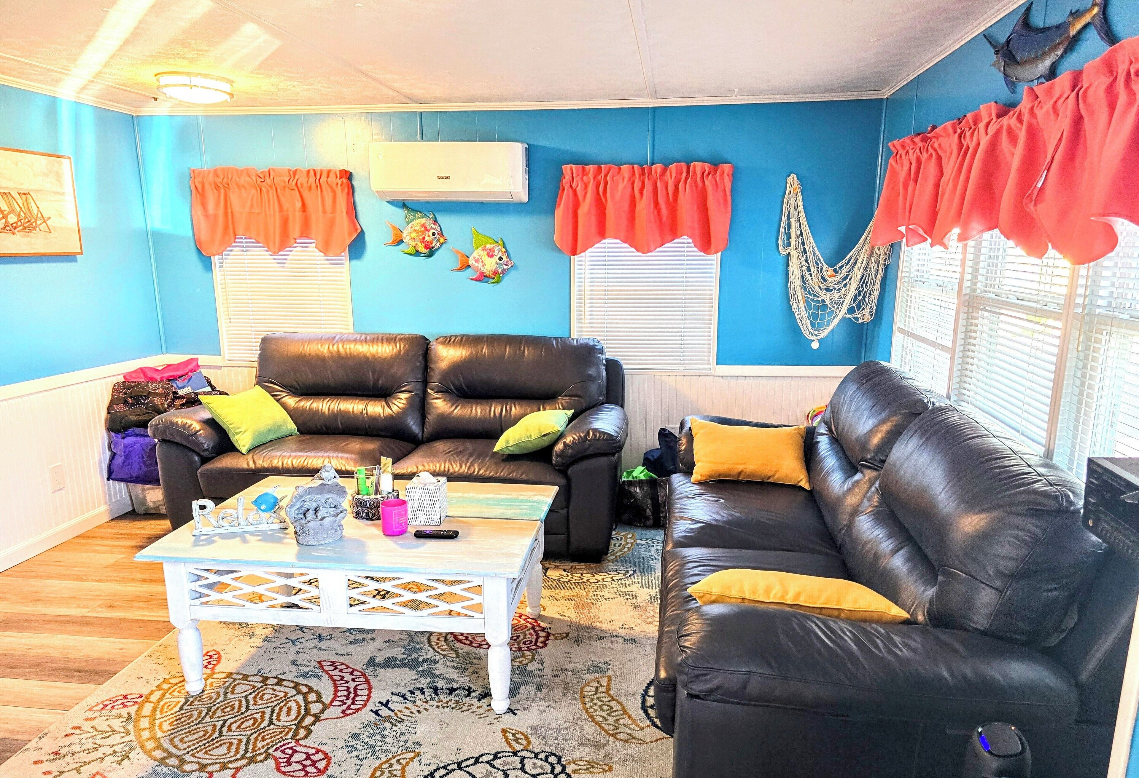 A living room with two black leather sofas, a white coffee table, and a patterned rug.