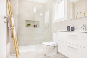 Un baño moderno con inodoro, ducha y tocador con espejo.