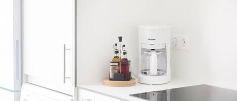 Eine moderne Küche mit Waschmaschine, Kaffeemaschine und einem Tablet auf der Arbeitsplatte.