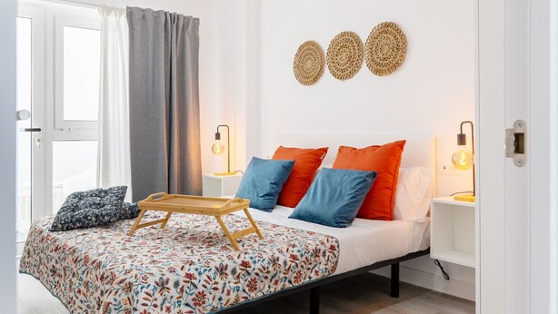 A modern bedroom with a bed, bedside tables, and a window with curtains.