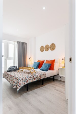 A modern bedroom with a bed, bedside tables, and a window with curtains. - Elegant Serenity at Apartment Carine (San Cristóbal de La Laguna)