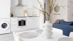 A modern kitchen with white cabinetry, a built-in oven, and a washing machine.