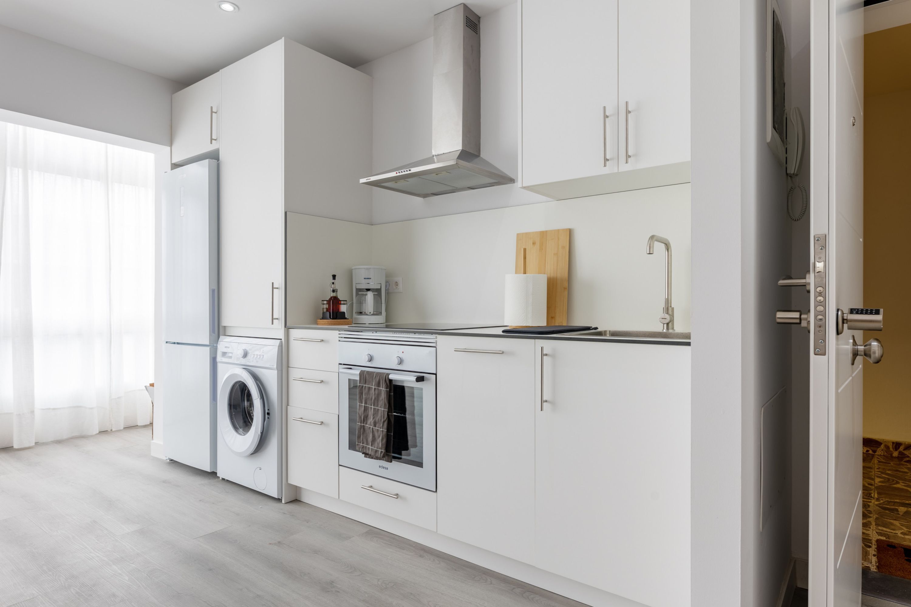 A modern kitchen with a built-in washer, oven, and a stainless steel range hood.