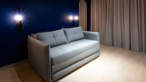 Una sala de estar moderna con un sofá gris, dos luces fijadas a la pared y una cortina.