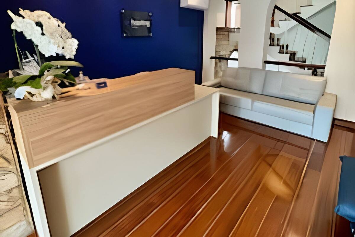 Un'area reception con una scrivania in legno, una parete d'accento blu e una scala sullo sfondo.