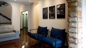 Un salón moderno con un sofá blanco, dos sillones azules y una pared de acento de piedra.