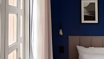 A hotel room with a bed, a wall-mounted air conditioner, and a framed picture.